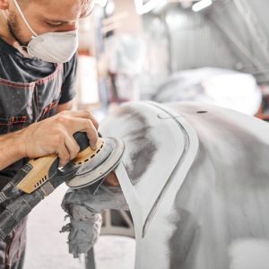 The,Mechanic,Works,With,A,Grinding,Tool.,Sanding,Of,Car The,Mechanic,Works,With,A,Grinding,Tool.,Sanding,Of,Car